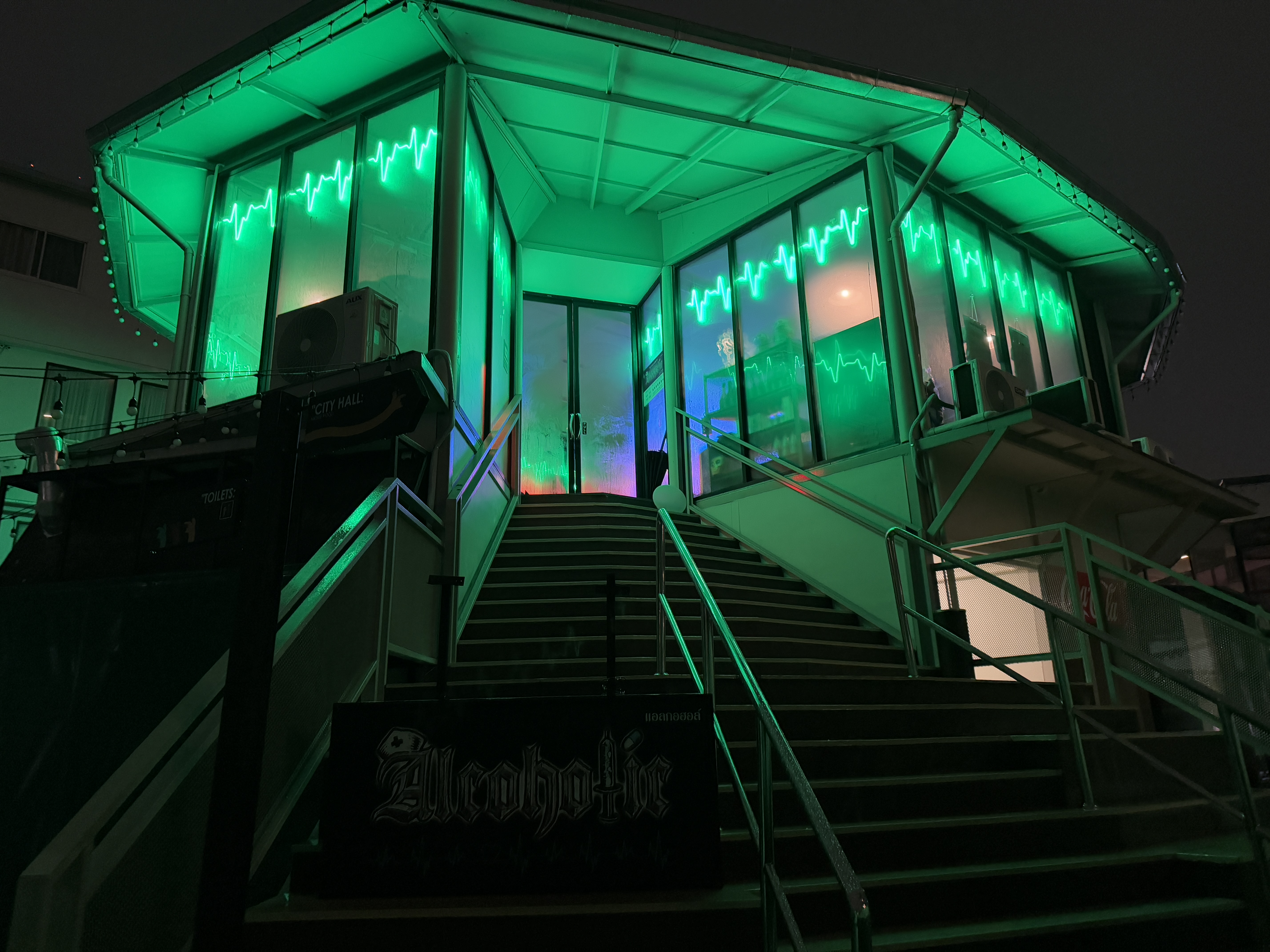 Alcoholic Thailand at night — neon-green EKG building